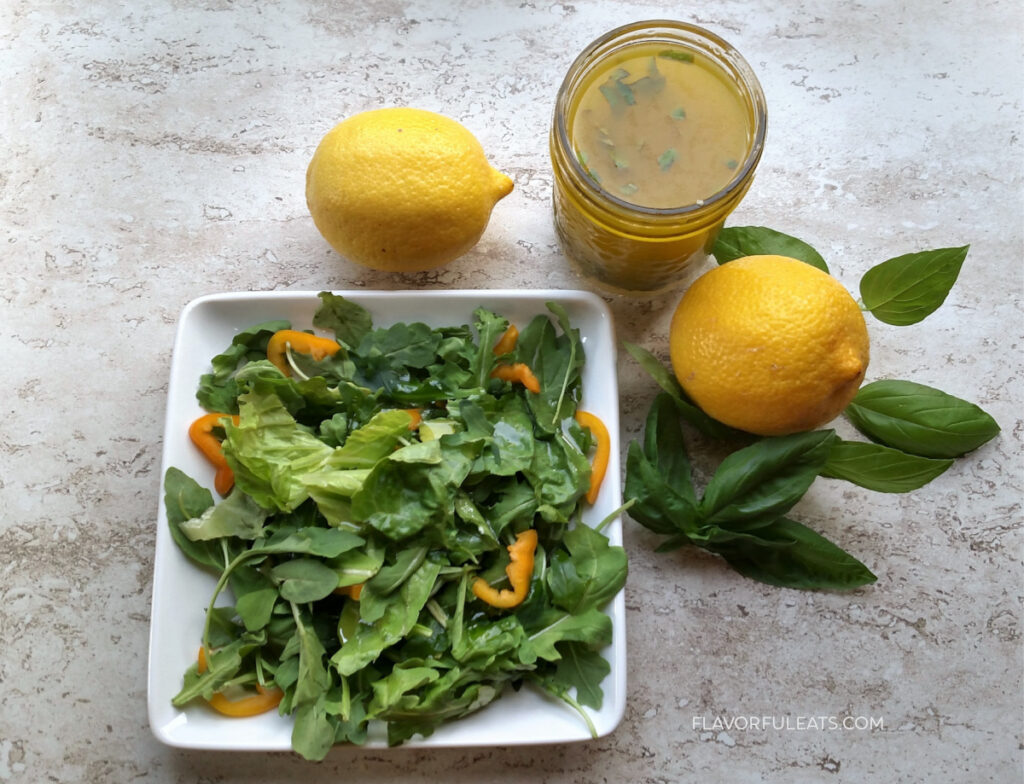 Lemon Basil Vinaigrette on a green salad with lemons next to it