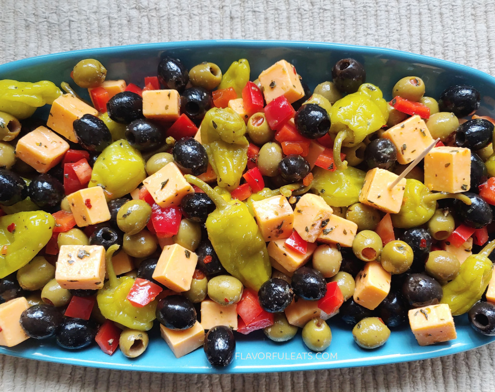A blue platter filled with Marinated Cheese & Olive Antipasto