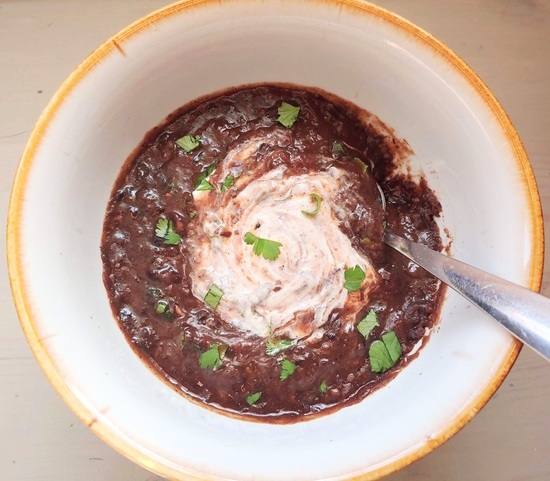 Bowl of black bean soup with sour cream swirled in.