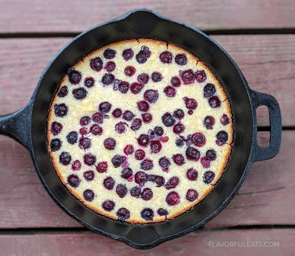 A cast iron skillet with a blueberry cake in it.