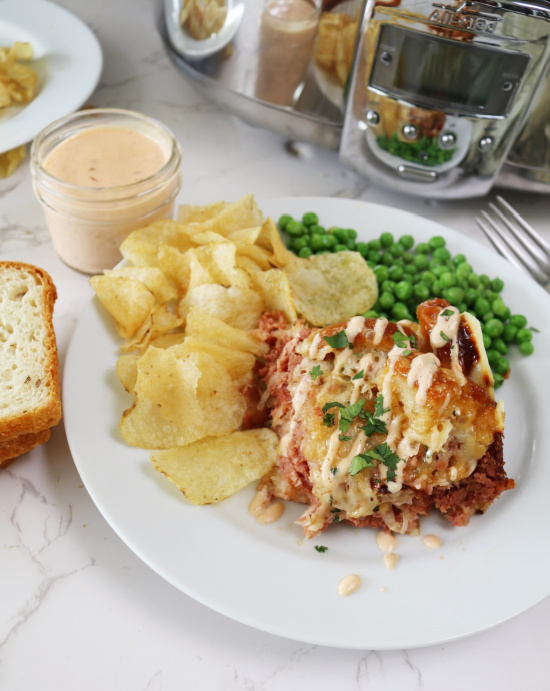 A plate of Reuben Casserole with peas and chips.